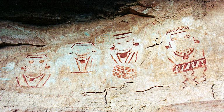 The Four Faces panel: four painted faces with necklaces and decorations