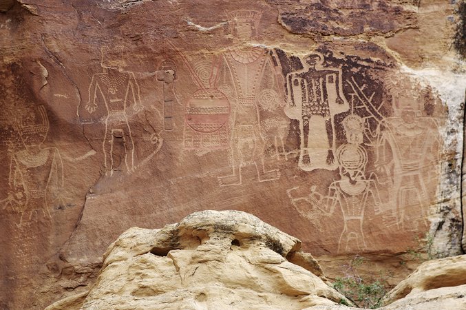 Large Fremont petroglyph panel of trapezoid-shaped figures with headdresses, necklaces and a round shield