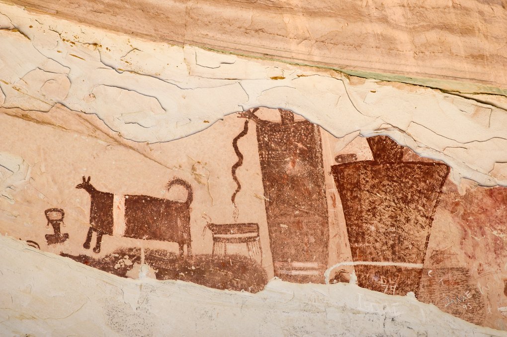 Dark-red painted figures beside a horned four-legged animal, a wavy snake and a small fringed object