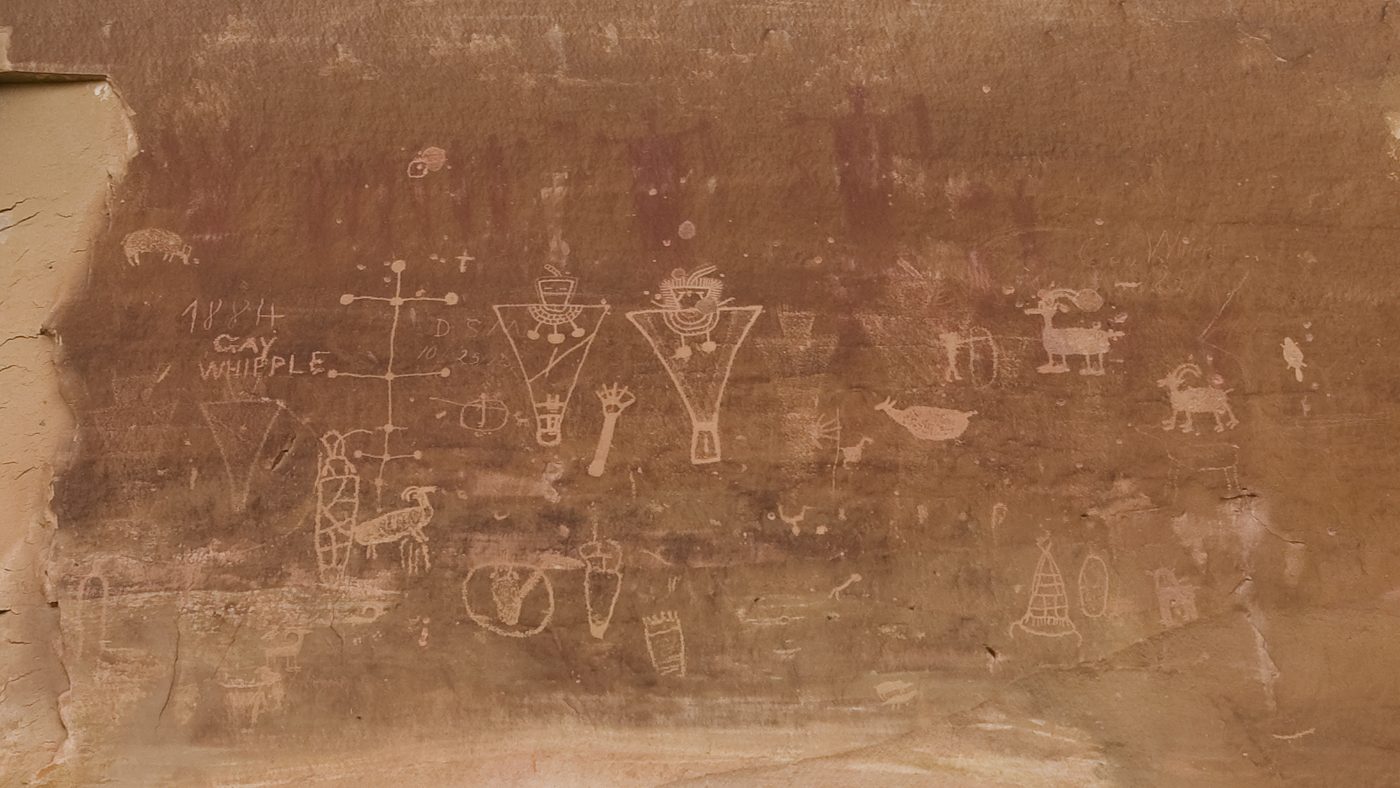 White Fremont figures painted over a faded older panel, with historic graffiti