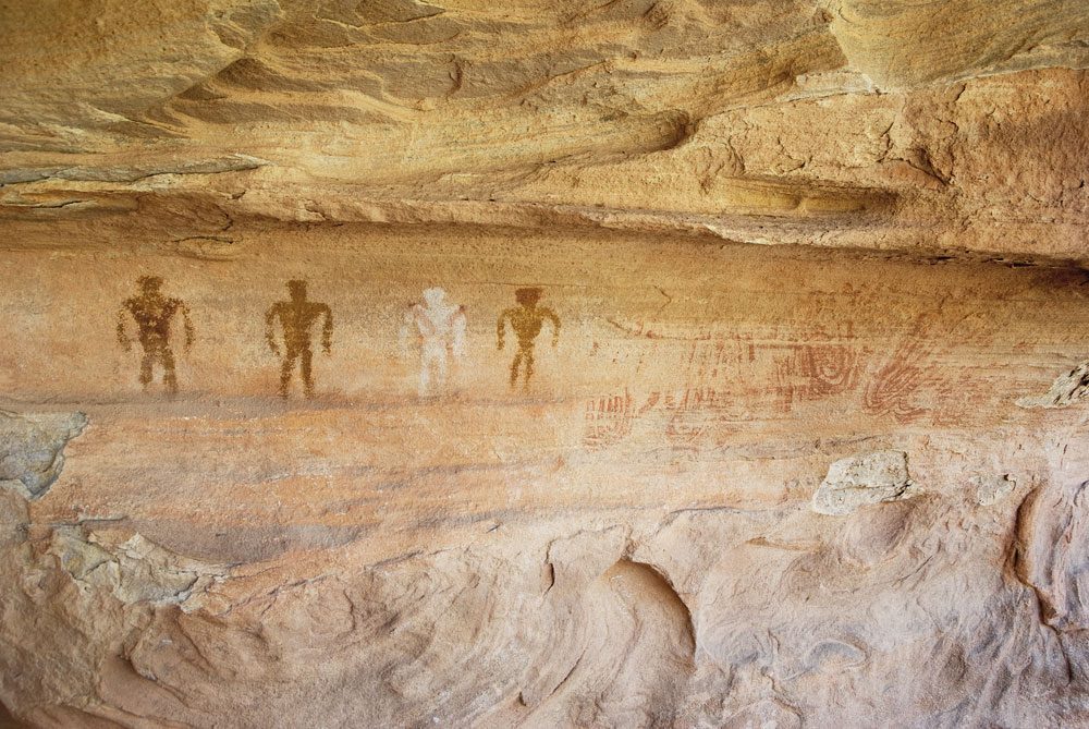 Large handprints and painted human-like figures in a rock shelter
