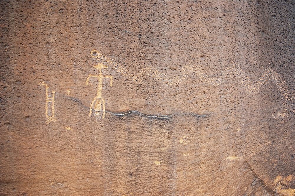 Petroglyph of a couple joined at the groin beside a figure giving birth