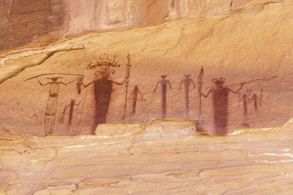 Row of Barrier Canyon Style figures holding long thin objects